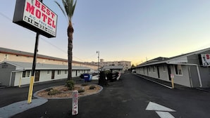 Un motel avec un panneau indicateur, un palmier et un ciel dégagé.