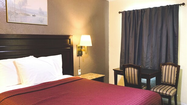Une chambre d’hôtel avec un grand lit, un bureau, une chaise, une lampe et un tableau au mur.