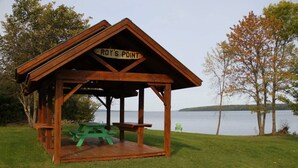 A wooden gazebo with a sign reading 'ROY'S POINT' and picnic tables. - Meadow Rue Retreat @ Brickyard Creek (Bayfield)