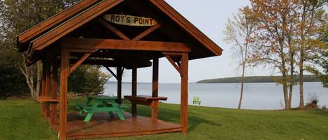 A wooden gazebo with a sign reading 'ROY'S POINT' and picnic tables.