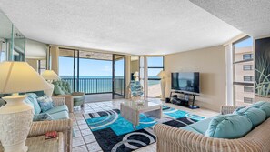 A spacious balcony with a view of the ocean, furnished with wicker furniture and a flat-screen TV. - Lighthouse Towers - 1808 (Clearwater)