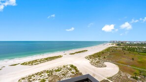 A beach with a clear view of the ocean and a distant cityscape. - Lighthouse Towers - 1808 (Clearwater)