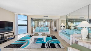 A spacious living room with a large TV, a sofa, and a coffee table. - Lighthouse Towers - 1808 (Clearwater)