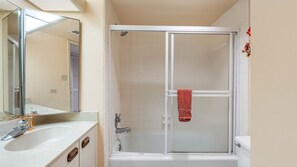 A bathroom with a shower, a sink, and a mirror. - Lighthouse Towers - 1808 (Clearwater)
