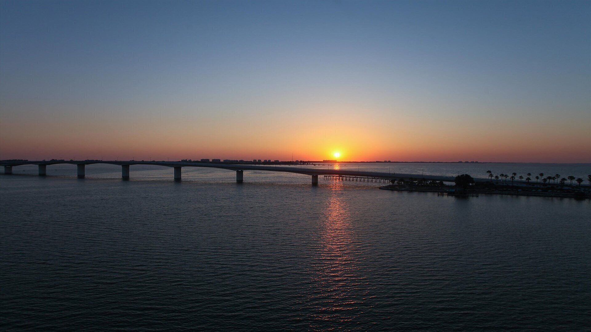 A bridge over water with a sunset in the background.