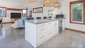 A modern kitchen with a central island, stainless steel appliances, and a large window. - Summer Palms - Tairua Holiday Home (Tairua)
