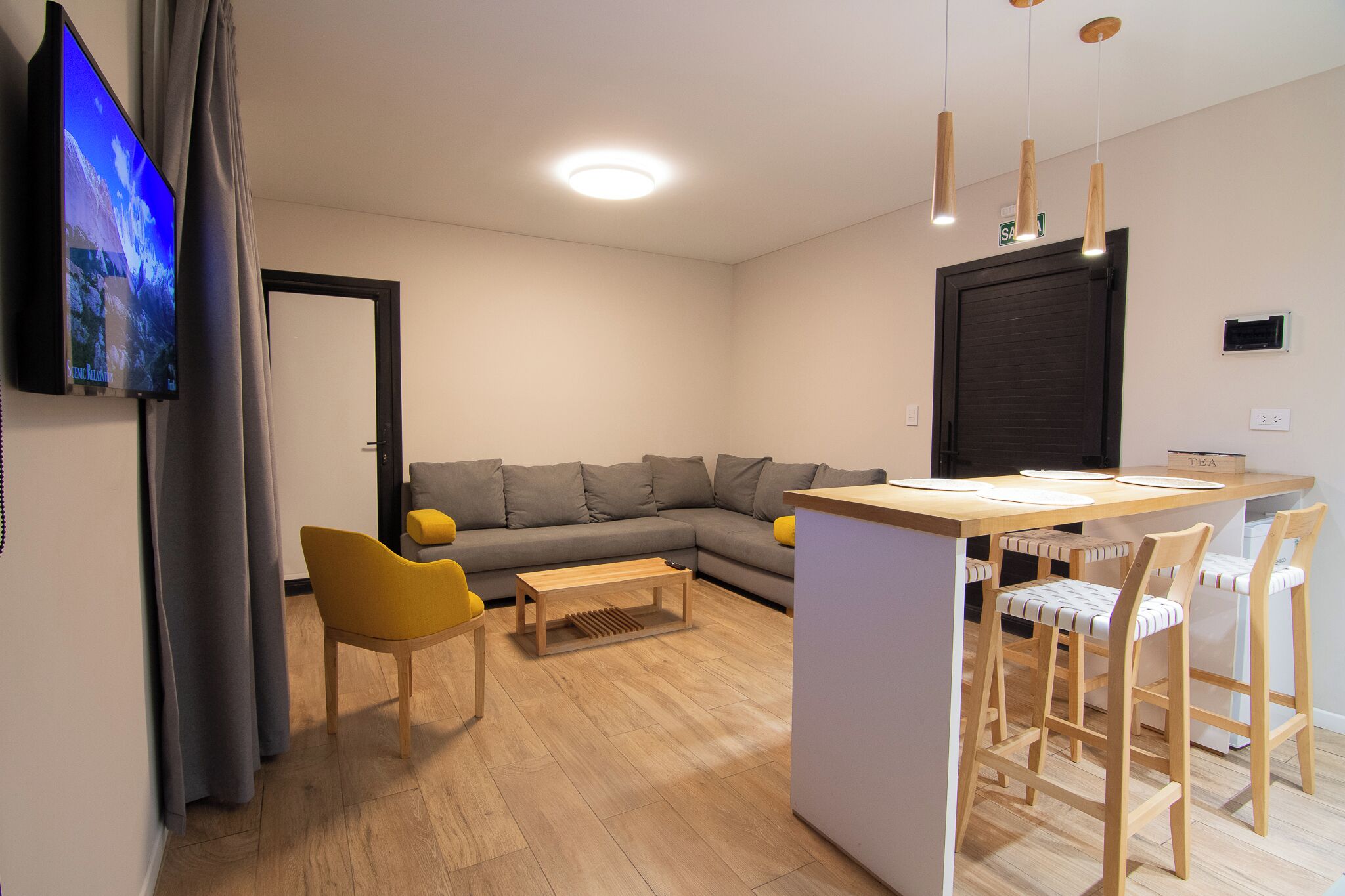 A modern living room with a sofa, a coffee table, and a TV mounted on the wall.
