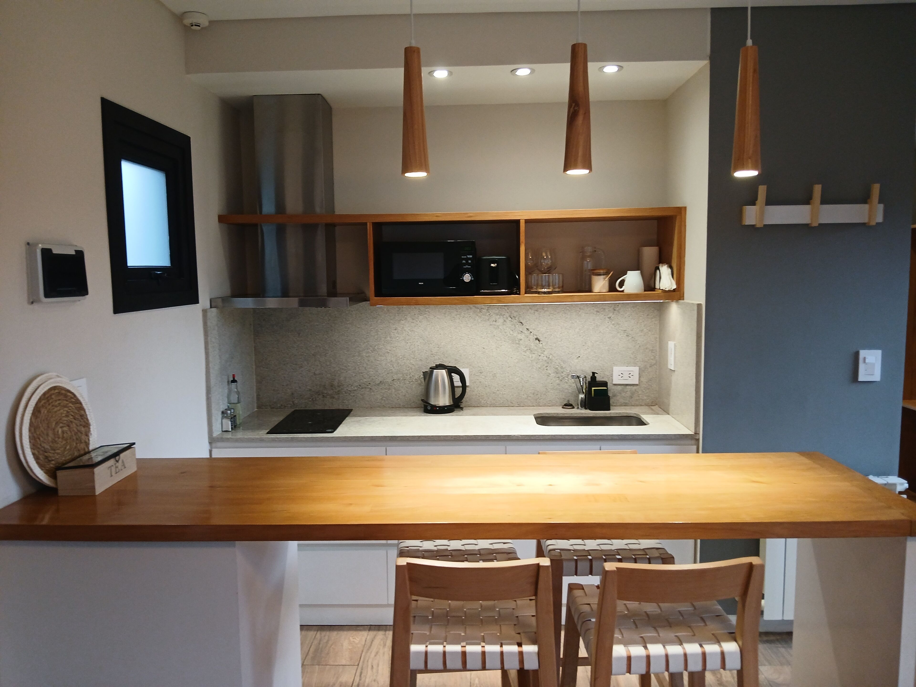 A modern kitchen with a wooden island, pendant lights, and a built-in microwave.