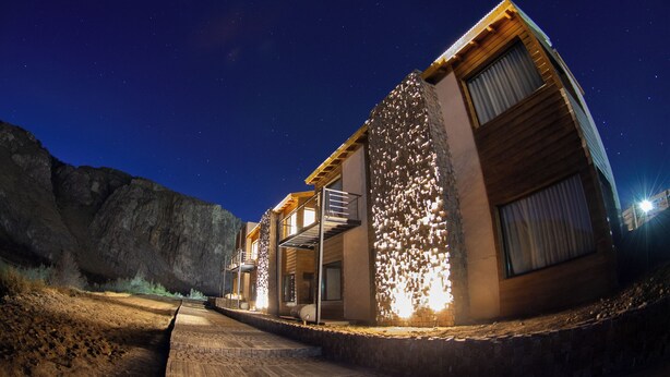 Un bâtiment moderne avec une façade en pierre, une terrasse en bois et un escalier menant à un balcon.