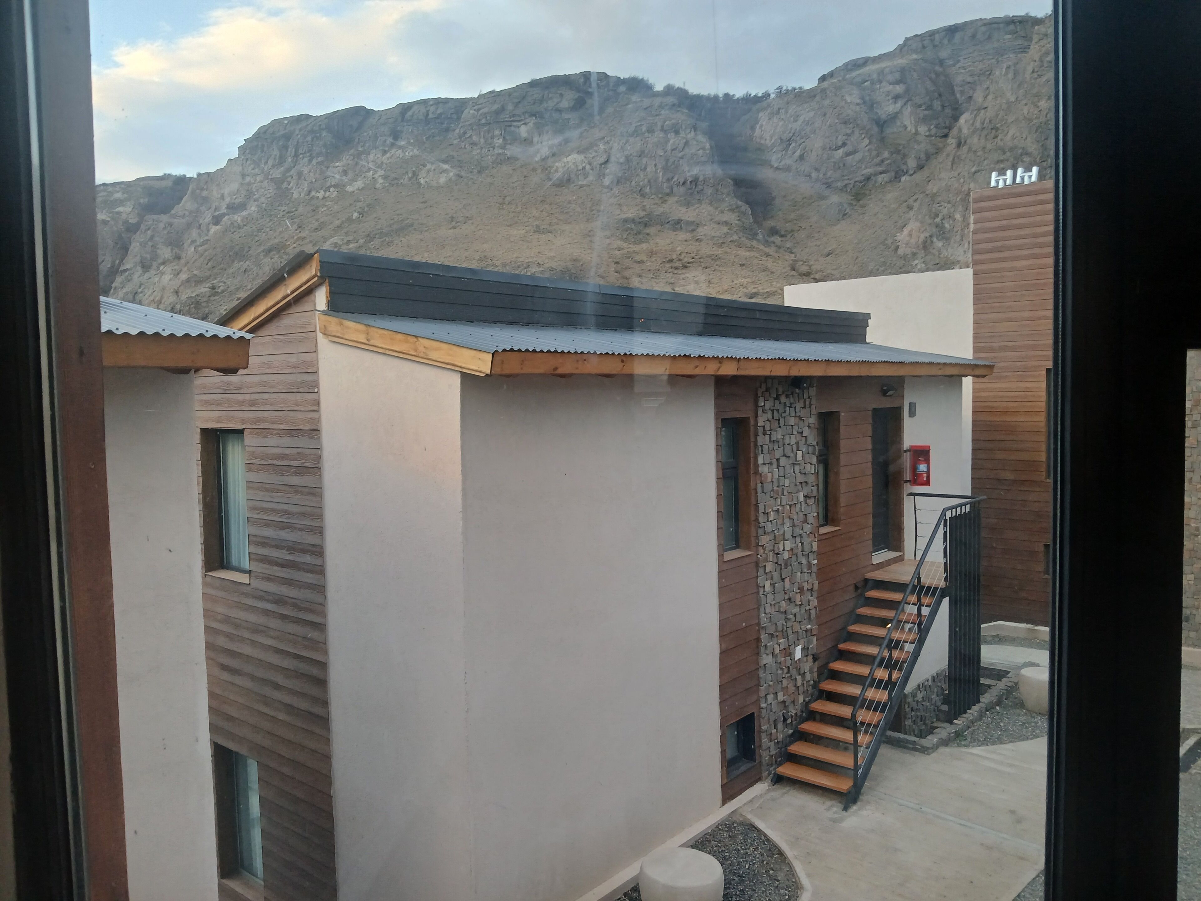 Un bâtiment moderne doté d’un escalier, d’un extincteur et offrant une vue sur un paysage montagneux.