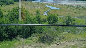 Une vue depuis un balcon donnant sur une rivière, avec des montagnes en arrière-plan.
