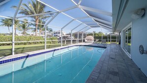 A pool with a clear blue tile border, surrounded by a covered patio area with a white roof structure. - Cozy retreat with Modern Comforts (Marco Island)