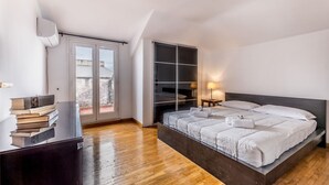 A bedroom with a large bed, a sliding glass door to the outside, a built-in wardrobe, and a bedside table with a lamp. - Conca dóro - Val Dála Retreat (Rome)