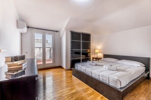 Ein Schlafzimmer mit einem großen Bett, einer Glastür zum Außenbereich, einem eingebauten Kleiderschrank und einem Nachttisch mit Lampe.