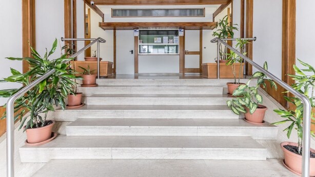 A staircase with terracotta pots on each side, leading to a reception area with a glass door and a sign above it. - Conca dóro - Val Dála Retreat (Rome)
