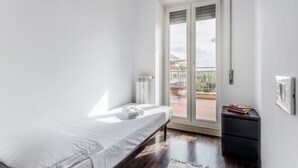 A minimalist bedroom with a single bed, a black nightstand, and a view of a balcony. - Conca dóro - Val Dála Retreat (Rome)