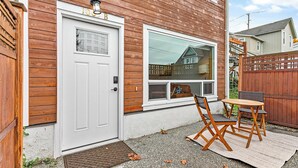 Una casa de madera con una puerta blanca, una ventana y un patio con una mesa y sillas.