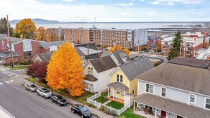 Un barrio residencial con casas, una calle y vistas al agua y montañas a lo lejos.