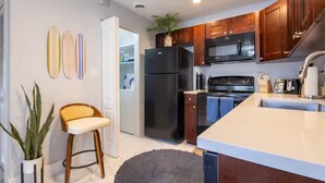 A modern kitchen with dark wood cabinets, a black refrigerator, a stainless steel microwave, and a large island with a sink.
