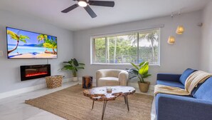 A modern living room with a TV, fireplace, sofa, and large windows.