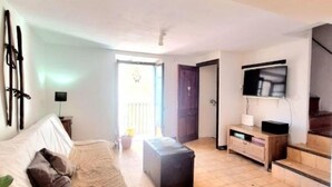 Una sala de estar con una cama, una mesa de centro, un televisor y una escalera.
