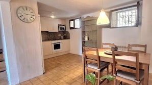 Una cocina amplia con comedor, un reloj en la pared y una planta en maceta.