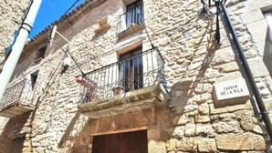 Un edificio de piedra con puerta de madera, un pequeño balcón y un cartel que dice