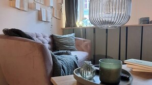 Ein gemütliches Wohnzimmer mit Holzbalkendecke, einer Couch, einem Couchtisch mit einer grünen Pflanze und einer Wand mit gerahmten Papieren.