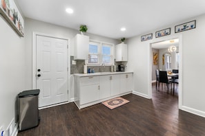A modern kitchen with white cabinetry, a built-in stove, and a dining area with a table and chairs. - Large 3BR Home Near Dulles w/parking sleeps 8 (Centreville)