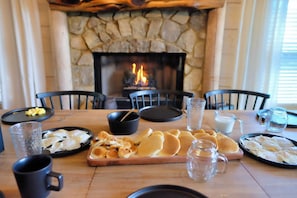 A dining table set for breakfast with pancakes, eggs, and beverages, in front of a stone fireplace. - Whippoorwill Estate - Spa | Mini Golf | B Ball (Mineral Bluff)