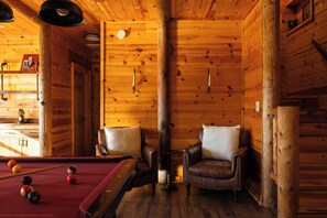 A cozy wooden cabin interior with a pool table, two leather armchairs, and a fireplace. - Whippoorwill Estate - Spa | Mini Golf | B Ball (Mineral Bluff)