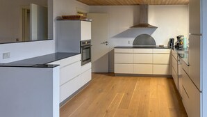 Eine moderne Küche mit weißen Schränken, Holzboden und einer Edelstahl-Dunstabzugshaube.