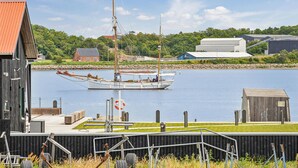 Ein Hafen mit einem Segelboot an Deck, ein Holzen Gebäude und ein Rasenstück mit einem Zaun.