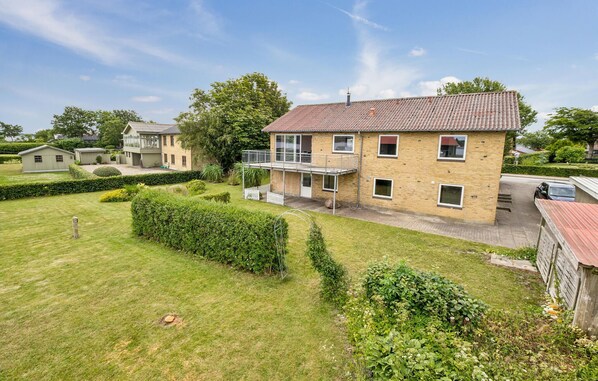A two-story house with a balcony, surrounded by well-maintained lawns and hedges. - Gorgeous home in Thisted with house sea view (Thisted)