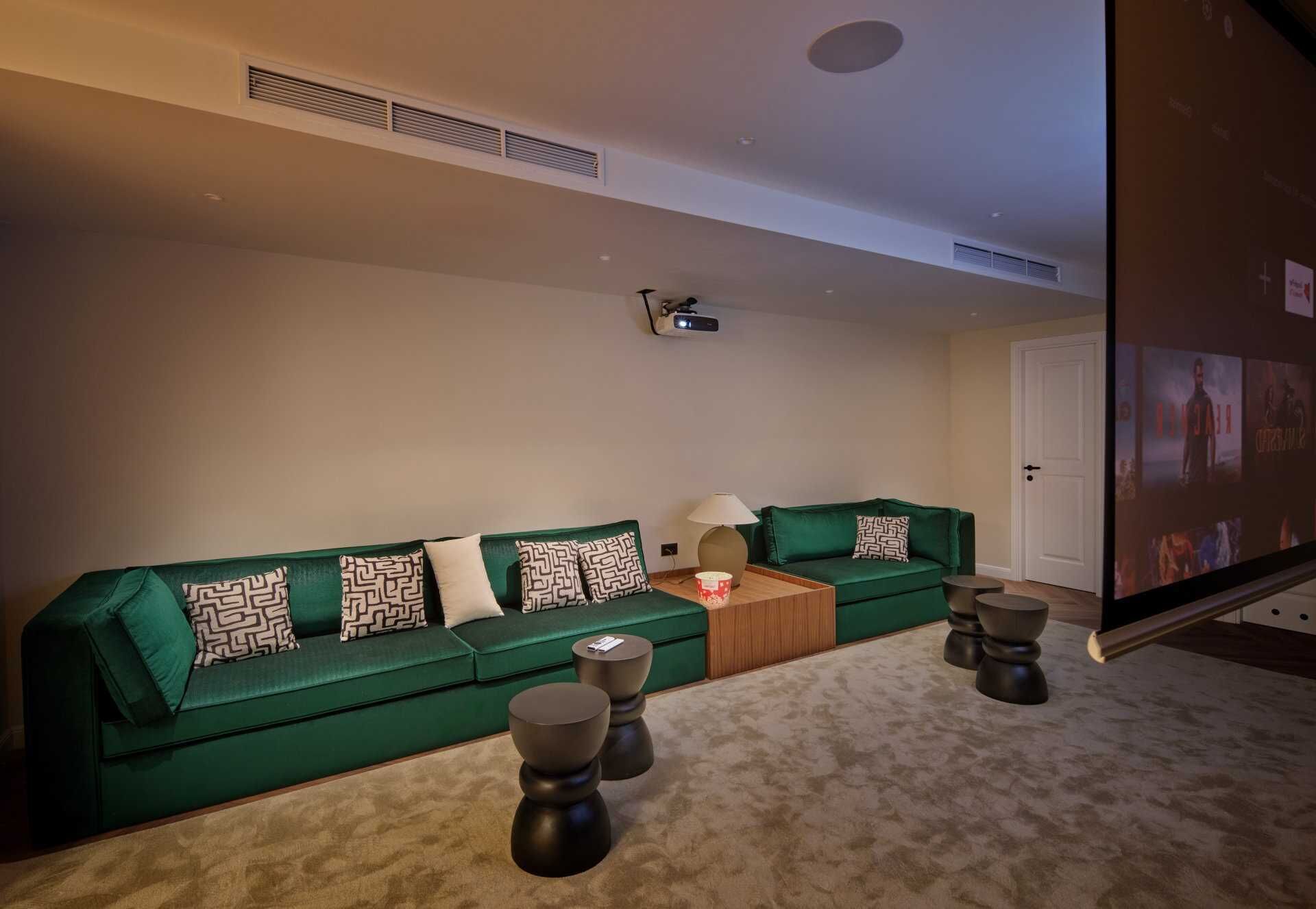 Ein Wohnzimmer mit einem grünen Sofa, gemusterten Kissen, einem Couchtisch und einem Fernseher.