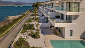 Un hotel moderno con piscina, zona de estar exterior y vistas al mar.