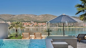 A pool area with lounge chairs, a view of a coastal town, and a large umbrella structure. - Luxury Villa Lunea with Pool VII (Trogir)