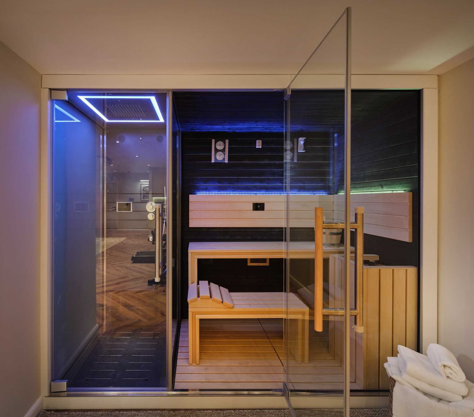 A modern, compact room with a glass partition, a bunk bed, a wooden bench, and a small table.