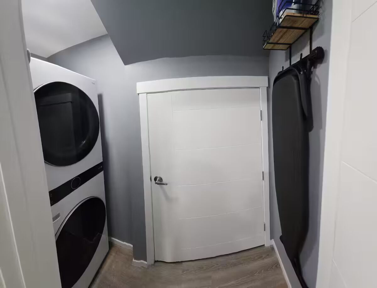 Une buanderie avec une porte blanche, un lave-linge et un étendoir.
