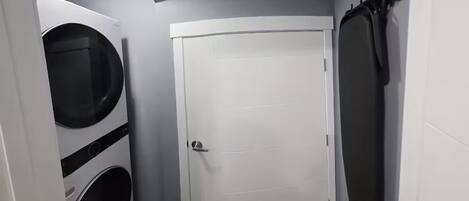 A laundry room with a white door, a washing machine, and a drying rack.