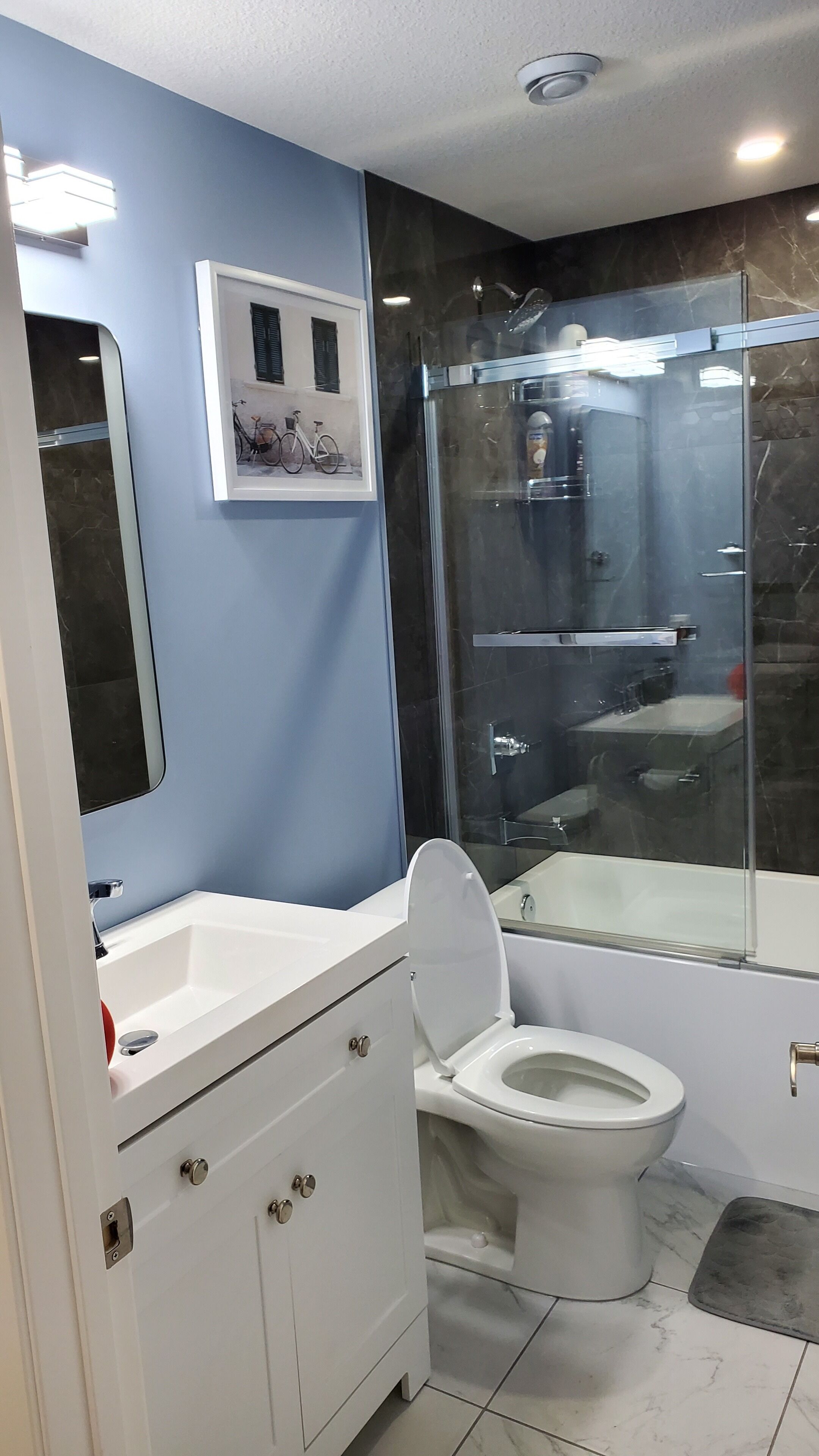 Un baño moderno con un lavamanos blanco, un inodoro y una ducha con mampara de vidrio.