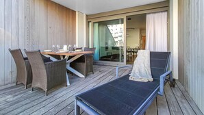 A balcony with a dining table set for four, surrounded by wicker chairs. - Cozy apartment in Oostende (Oostende)