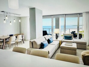 A modern hotel room with a large balcony, a dining area, and a seating area with a view of the sea. - Marriott Crystal Shores Two Bedroom Gulf View Villa (Marco Island)