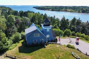 A blue house with a tower, surrounded by greenery and a body of water. - Coastal Lighthouse Retreat 4mi to Acadia
Sleeps 16 guest (Tremont)