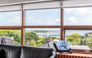 A room with large windows, a view of a body of water, and a table with a decorative glass.