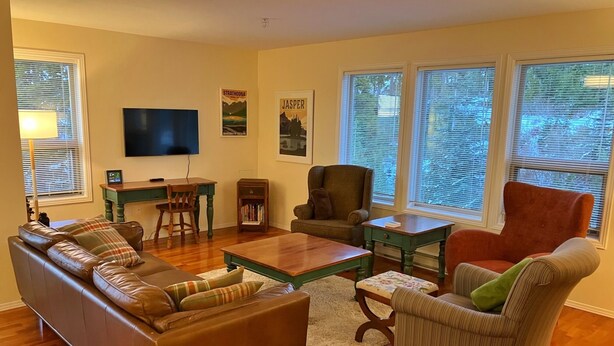 Een woonkamer met een bank, fauteuils, een salontafel, een televisie en een boekenkast.