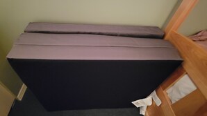 Een kamer met een bed, een houten hoofdeinde en een beklede bank in zwart en grijs.