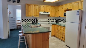 A kitchen with wooden cabinets, a white refrigerator, a stove, and a microwave. - Strathcona Views - Blueberry (Comox-Strathcona C)