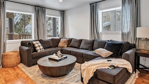Un salon moderne avec un canapé d’angle, une table basse ronde et une lampe.