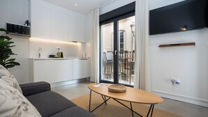 Een moderne woonkamer met een bank, een salontafel en een keukenhoek met een magnetron.